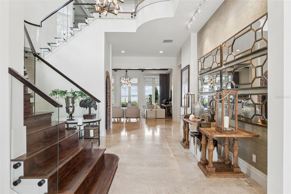 A grand foyer features a wooden staircase, stone flooring, and a console table with mirrors — 9236 BAY POINT DRIVE, ORLANDO, FL