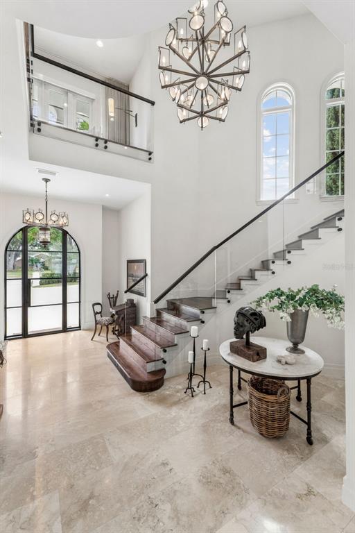 A grand foyer features a marble floor, a floating staircase, and a large modern chandelier — 9236 BAY POINT DRIVE, ORLANDO, FL
