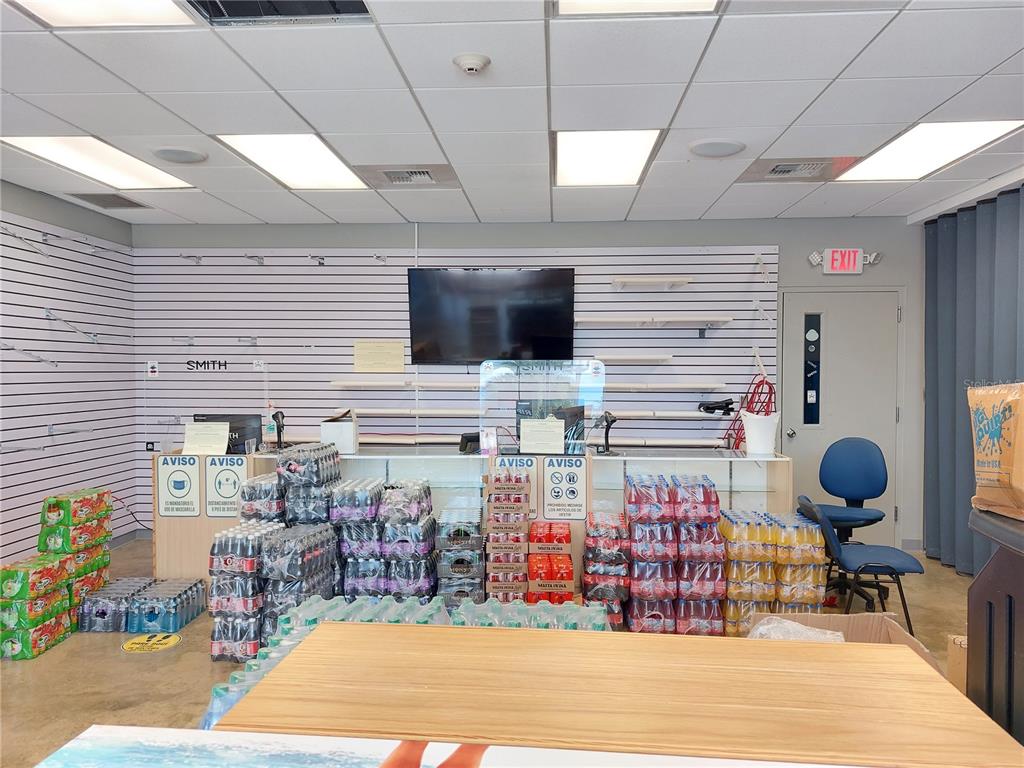 A retail space features a service counter, slatwall shelving, and stacks of bottled beverages — Bo Caín Alto LOCAL #2 SURF N' FUN WATER PARK, SAN GERMAN, PR