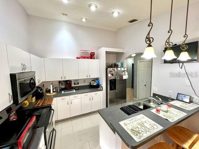 A kitchen features white cabinetry, stainless steel appliances, and a breakfast bar with pendant lights — 2814 PALM ISLE WAY, ORLANDO, FL