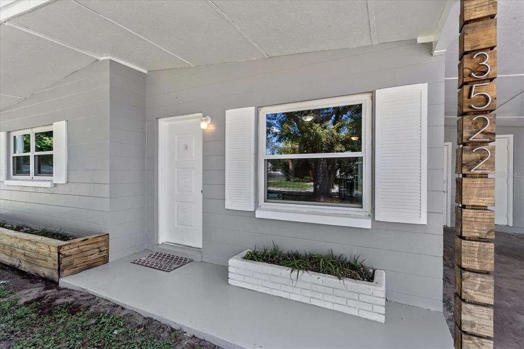 A gray house exterior features a white front door, a window with shutters, and planters — 3522 PRICE AVENUE, ORLANDO, FL