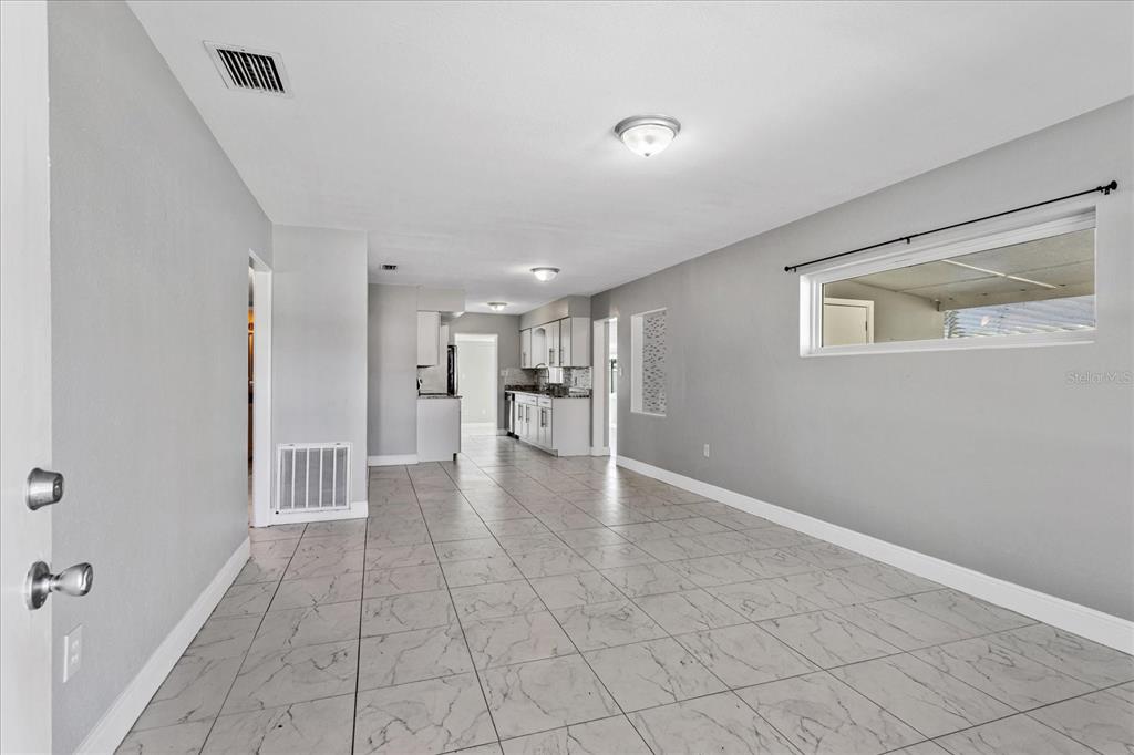 A bright, open-concept living area with light gray walls and white marble-patterned tile flooring — 3522 PRICE AVENUE, ORLANDO, FL