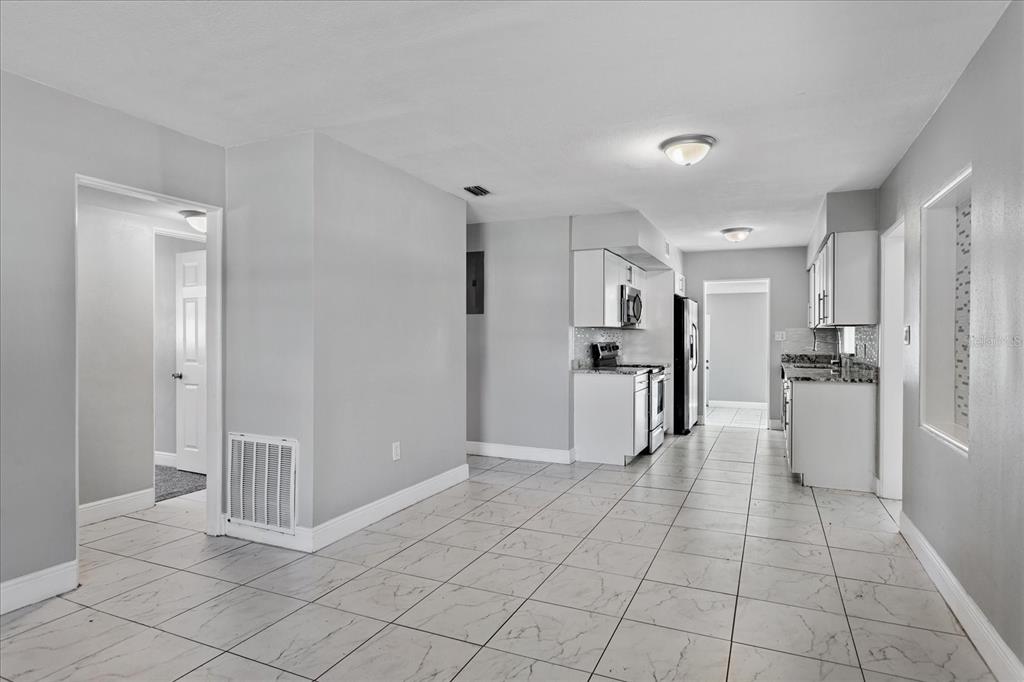 A kitchen and dining area with white cabinets, stainless steel appliances, and light tile flooring — 3522 PRICE AVENUE, ORLANDO, FL