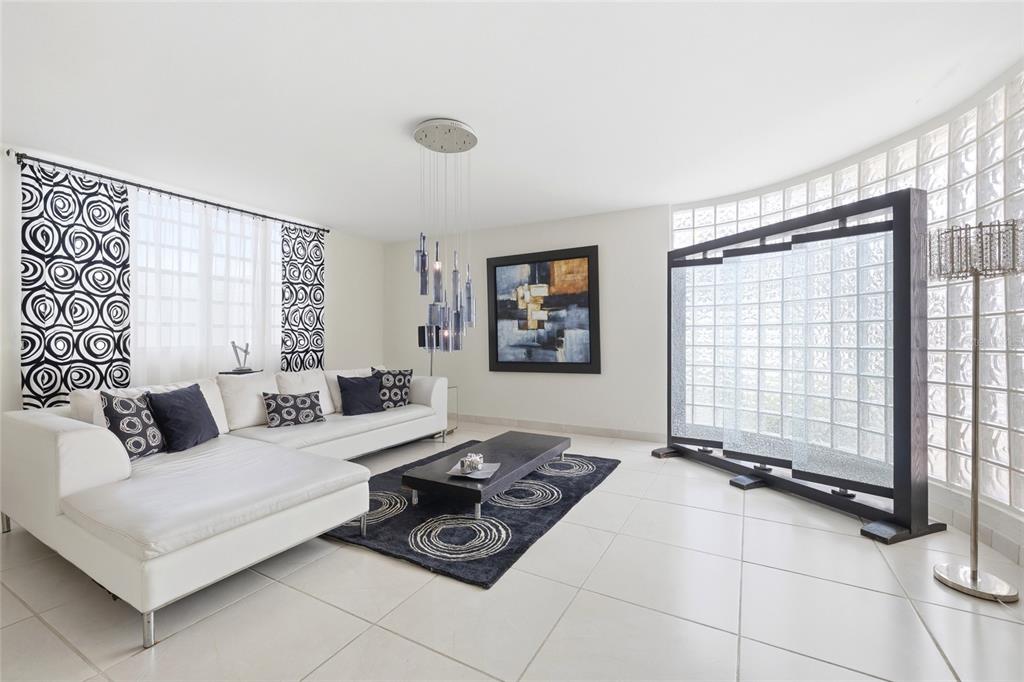 A modern living room features a white sectional sofa, a black coffee table, and glass blocks — 29 Calle 1 URB. SAN RAFAEL ESTATES, TRUJILLO ALTO, PR