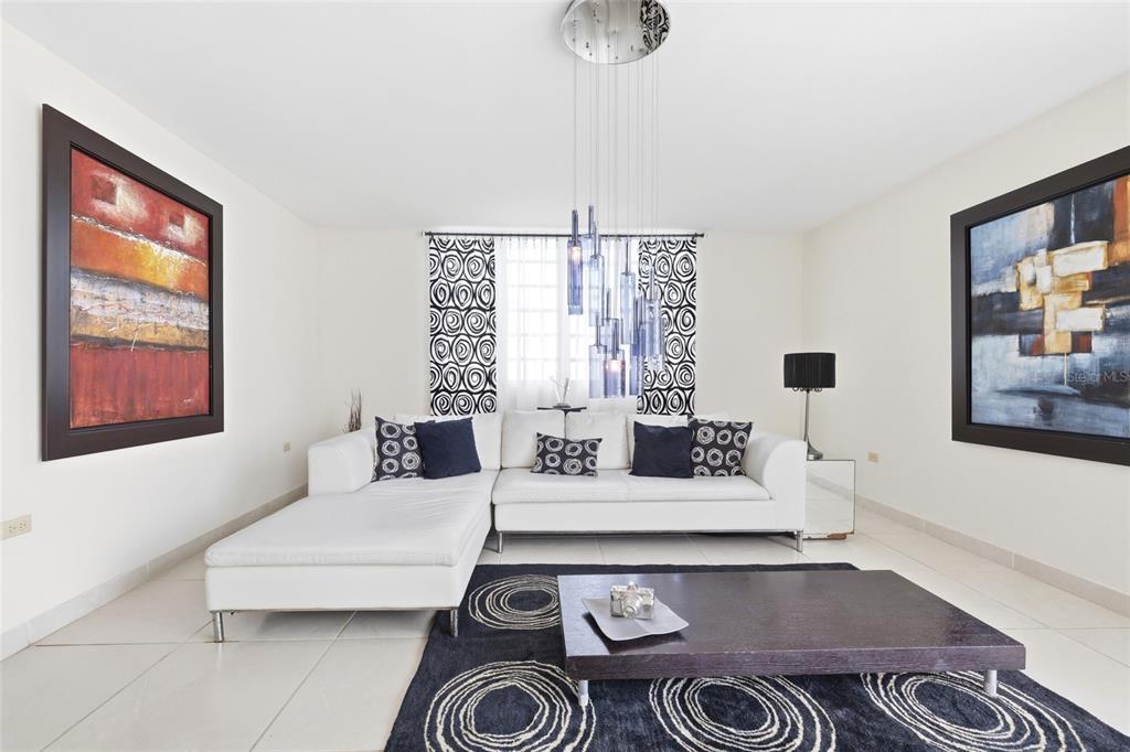 A modern living room features a white sectional sofa, a dark coffee table, and abstract art — 29 Calle 1 URB. SAN RAFAEL ESTATES, TRUJILLO ALTO, PR
