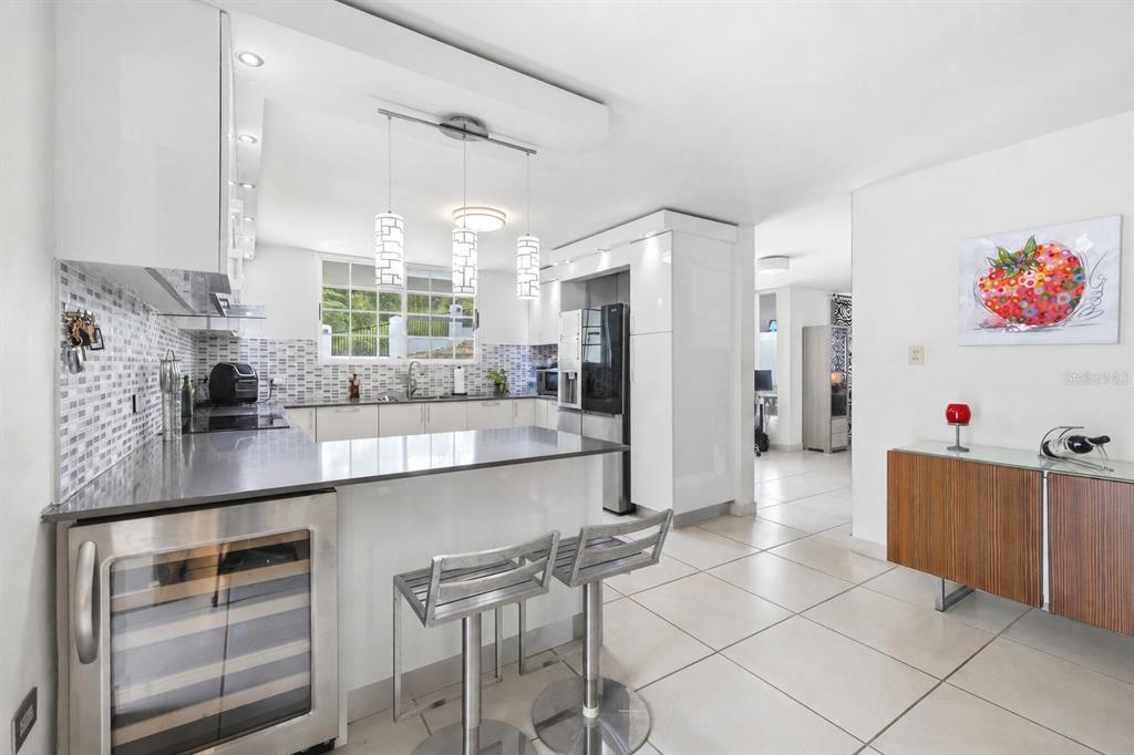 A modern kitchen features white cabinetry, stainless steel appliances, a breakfast bar, and tile flooring — 29 Calle 1 URB. SAN RAFAEL ESTATES, TRUJILLO ALTO, PR