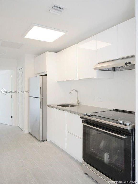 A modern kitchen features white cabinets, stainless steel appliances, and light-colored tile flooring — 620 Michigan Ave # 7, Miami Beach FL 33139, MIAMI BEACH, FL