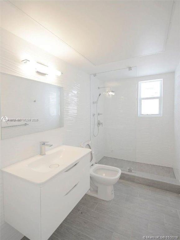 A modern bathroom features a white vanity, a glass-enclosed walk-in shower, and light gray flooring — 620 Michigan Ave # 7, Miami Beach FL 33139, MIAMI BEACH, FL