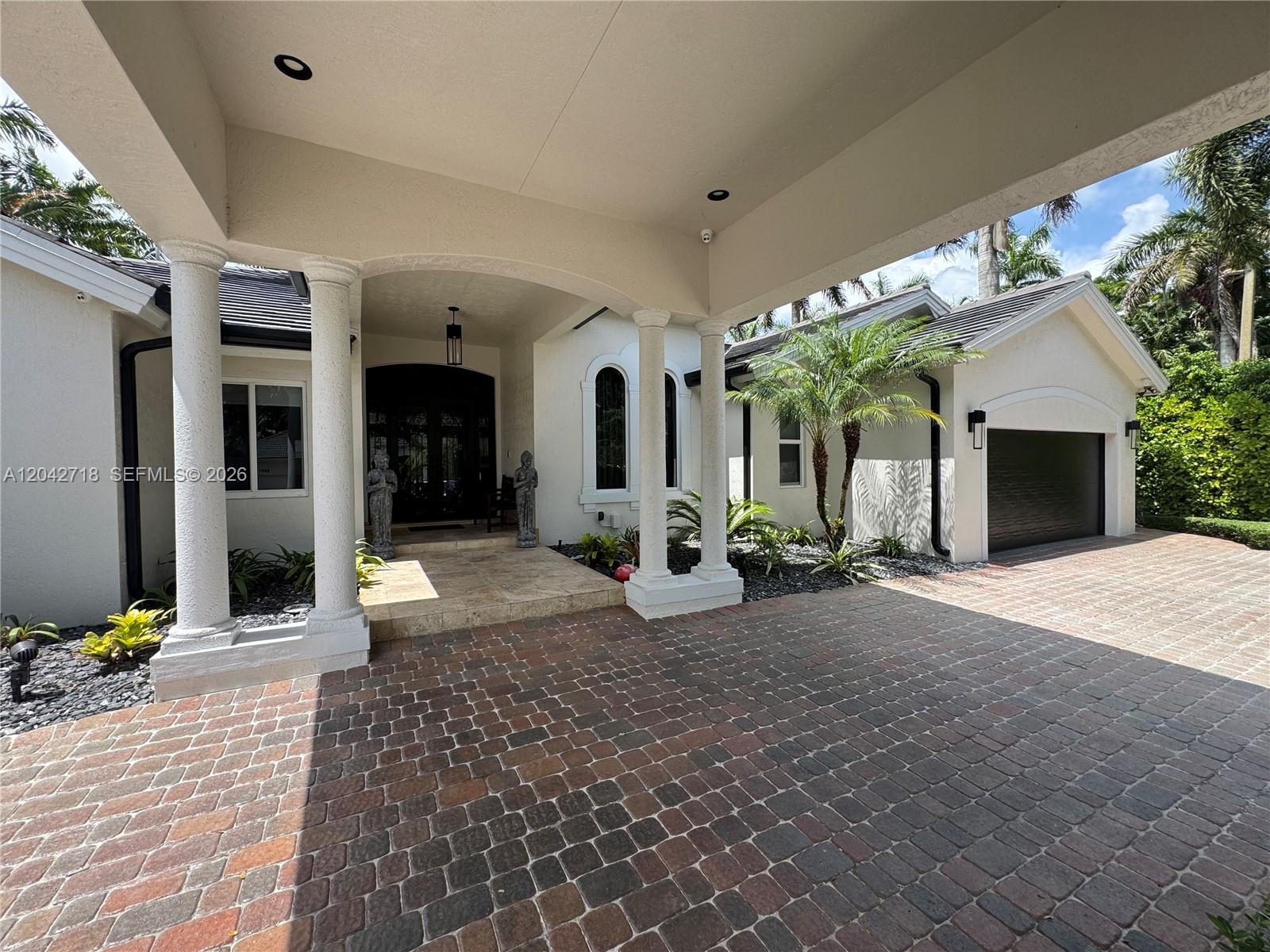 A paved driveway leads to a covered entryway with white columns and a garage — 9662 SW 123rd St, Miami FL 33176, MIAMI, FL