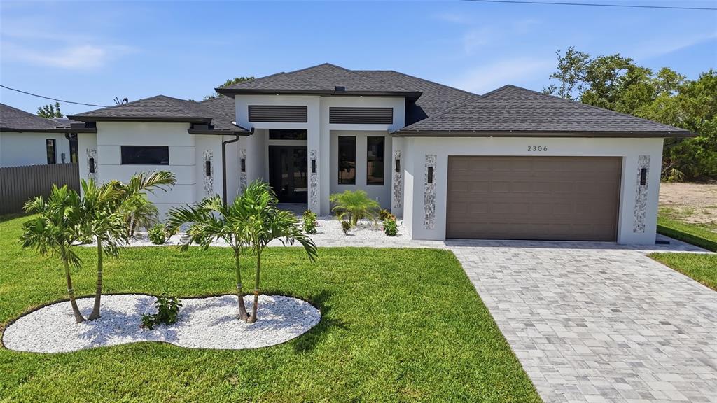 A modern single-story house features a paved driveway, white stucco exterior, and a two-car garage — 2306 SW 16TH TERRACE, CAPE CORAL, FL