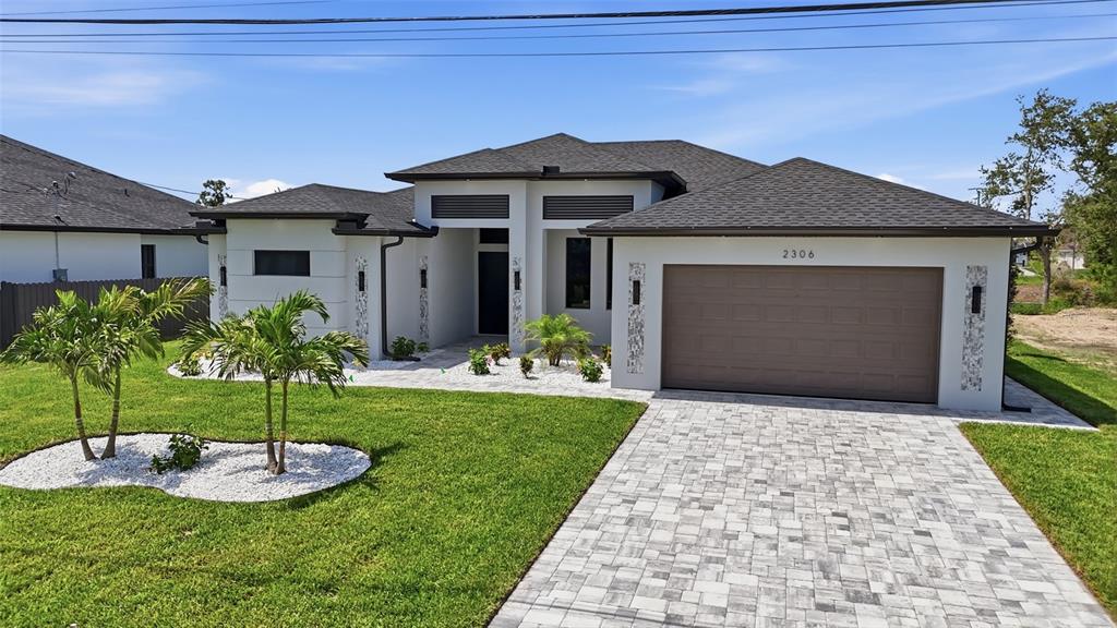 A modern single-story house with a two-car garage, white stucco exterior, and paved driveway — 2306 SW 16TH TERRACE, CAPE CORAL, FL