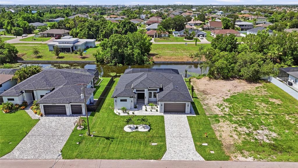 An aerial view shows two modern houses with paved driveways and a vacant lot nearby — 2306 SW 16TH TERRACE, CAPE CORAL, FL