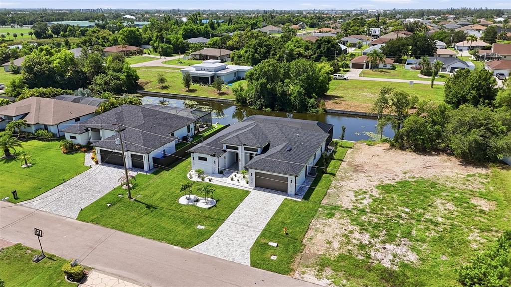 An aerial view shows two modern houses with dark roofs situated along a narrow canal — 2306 SW 16TH TERRACE, CAPE CORAL, FL