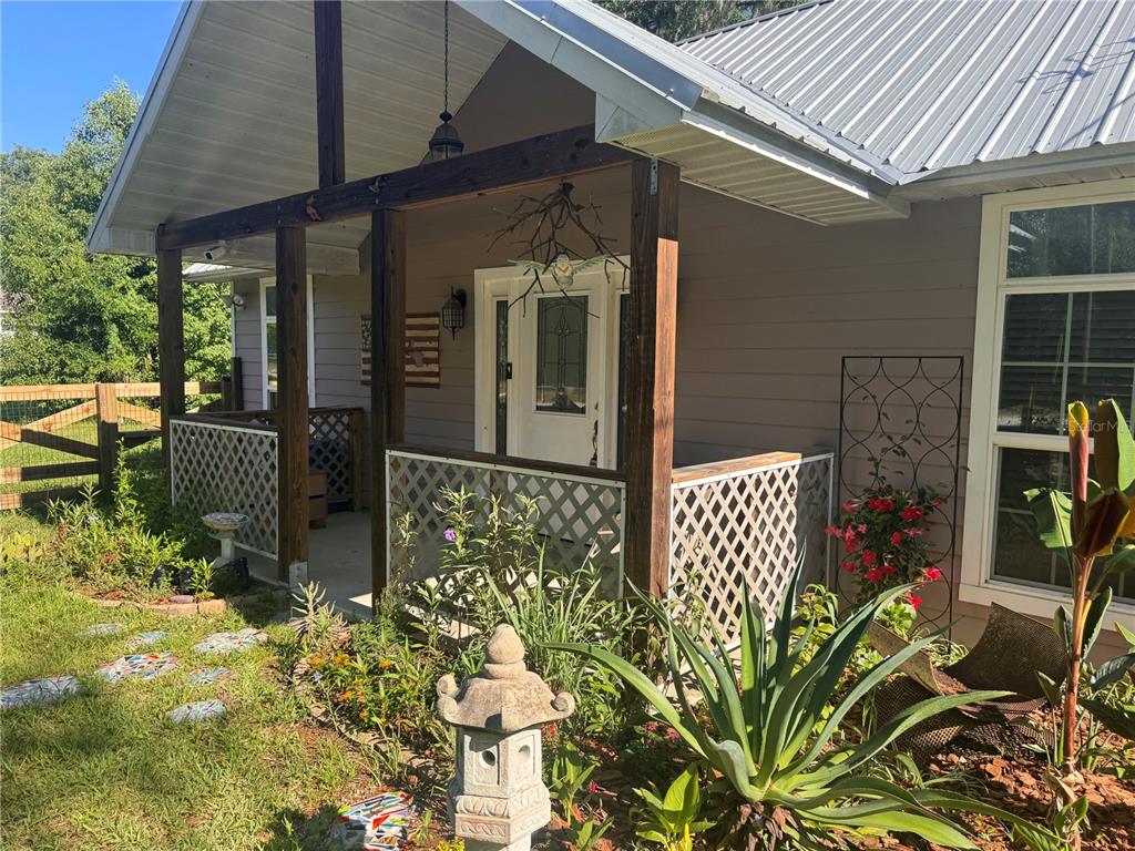 A front porch with a white lattice railing, wooden posts, and a metal roof — 103 GROVE STREET, MELROSE, FL