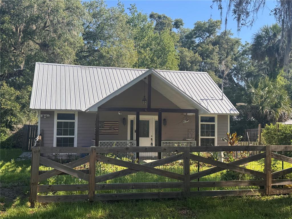 A small, gray cottage with a metal roof and a wooden fence in the front — 103 GROVE STREET, MELROSE, FL