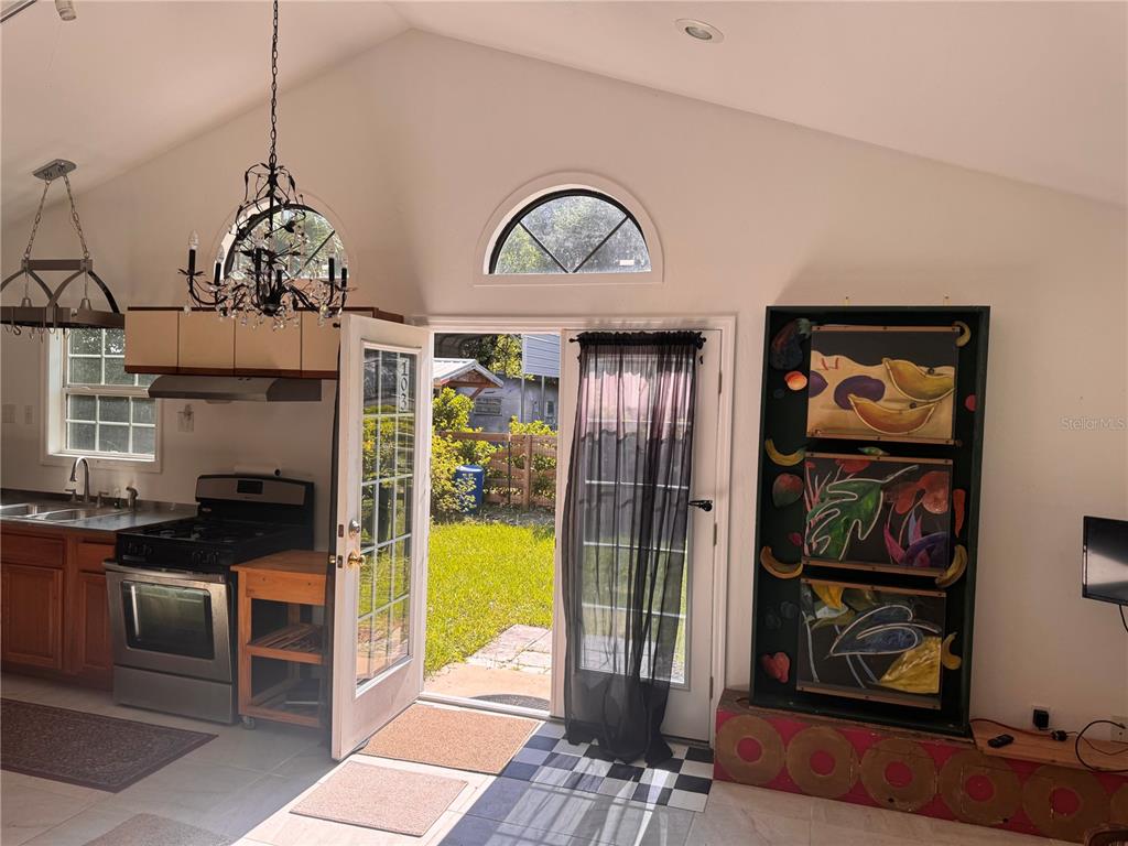 A kitchen with a vaulted ceiling, a chandelier, and a door leading to a backyard — 103 GROVE STREET, MELROSE, FL