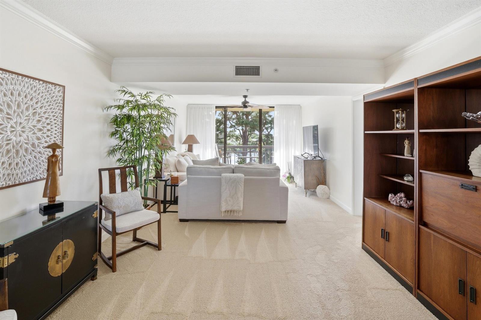 A living room features a sofa, a wooden bookshelf, a black cabinet, and a balcony view — 2101 Marina Isle Way # 404, Jupiter FL 33477, JUPITER, FL