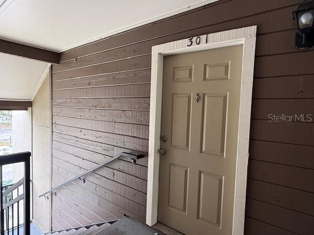 A tan apartment door labeled 301 is set into a brown horizontal wood-paneled exterior wall — 224 AFTON SQUARE UNIT 8-301, ALTAMONTE SPRINGS, FL