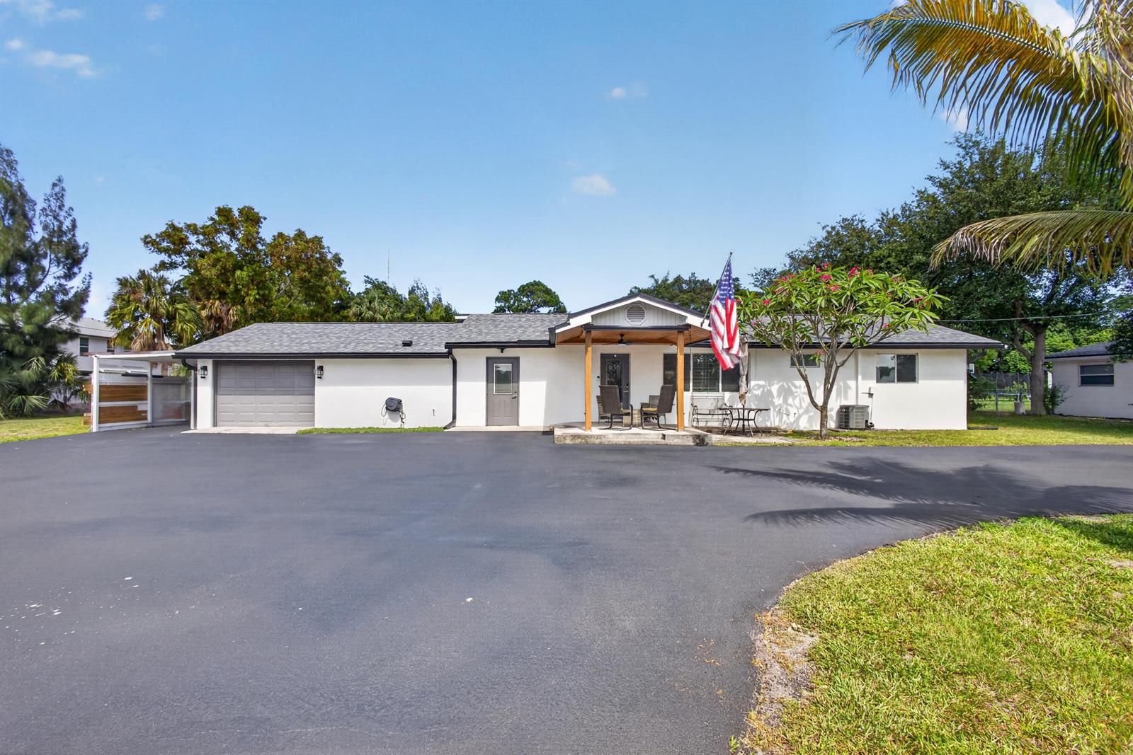 A single-story house with a white exterior, a gray roof, and a large paved driveway — 5500 West Place, Mangonia Park FL 33407, MANGONIA PARK, FL