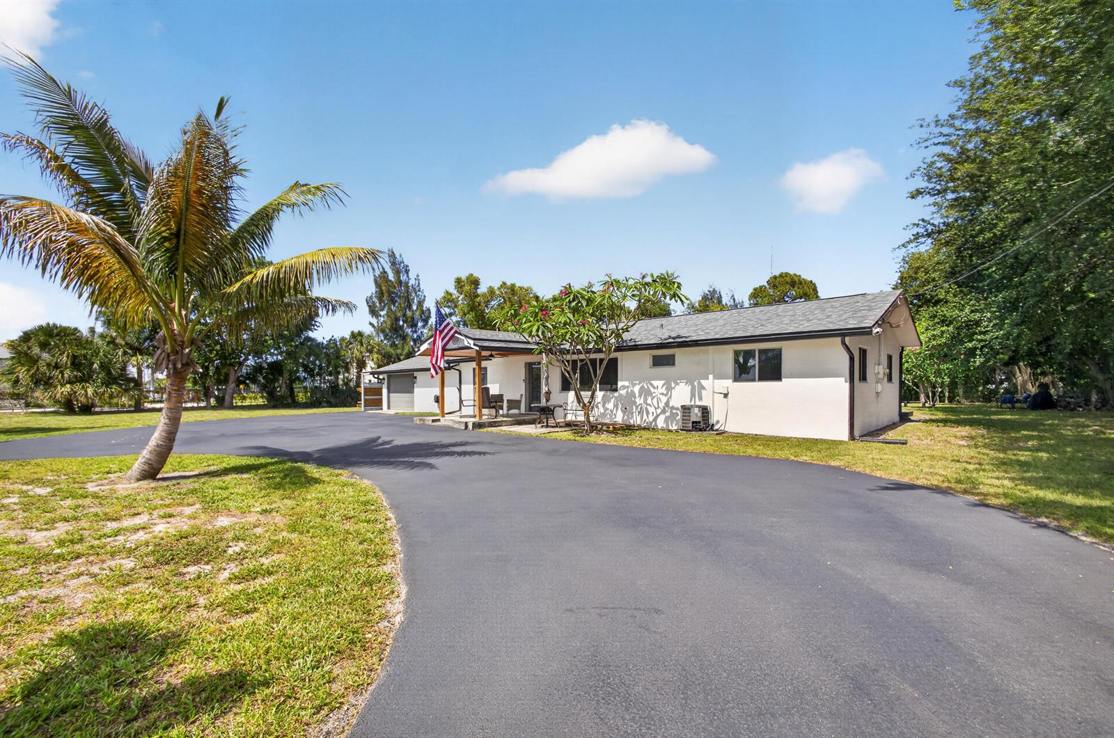 A single-story white house with a large asphalt driveway and a palm tree — 5500 West Place, Mangonia Park FL 33407, MANGONIA PARK, FL