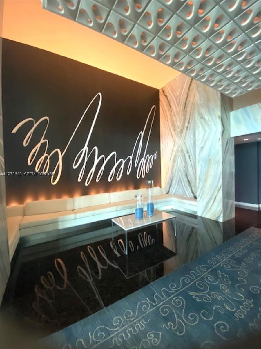 A modern lobby features a white sofa, a coffee table, and a large abstract wall mural — 335 S Biscayne Blvd # 1002, Miami FL 33131, MIAMI, FL