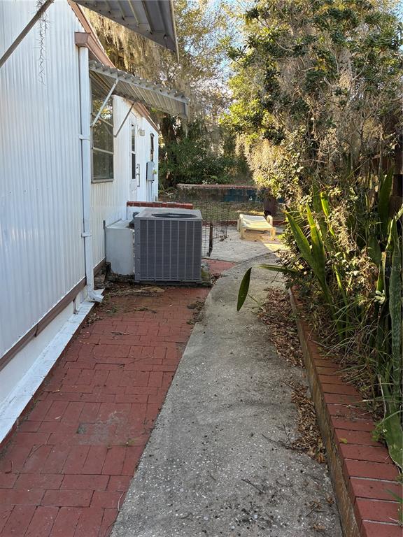 A side yard features a brick walkway, a concrete path, and an outdoor air conditioning unit — 3896 PICCIOLA ROAD UNIT 213, FRUITLAND PARK, FL