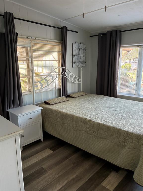 A bedroom features a white metal bed frame, dark curtains, and wood-look flooring — 3896 PICCIOLA ROAD UNIT 213, FRUITLAND PARK, FL