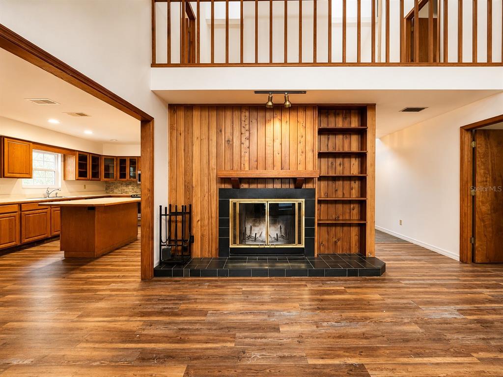 A living room features a wood-paneled fireplace, built-in shelving, and wood-look flooring — 7119 IMMOKALEE ROAD, KEYSTONE HEIGHTS, FL