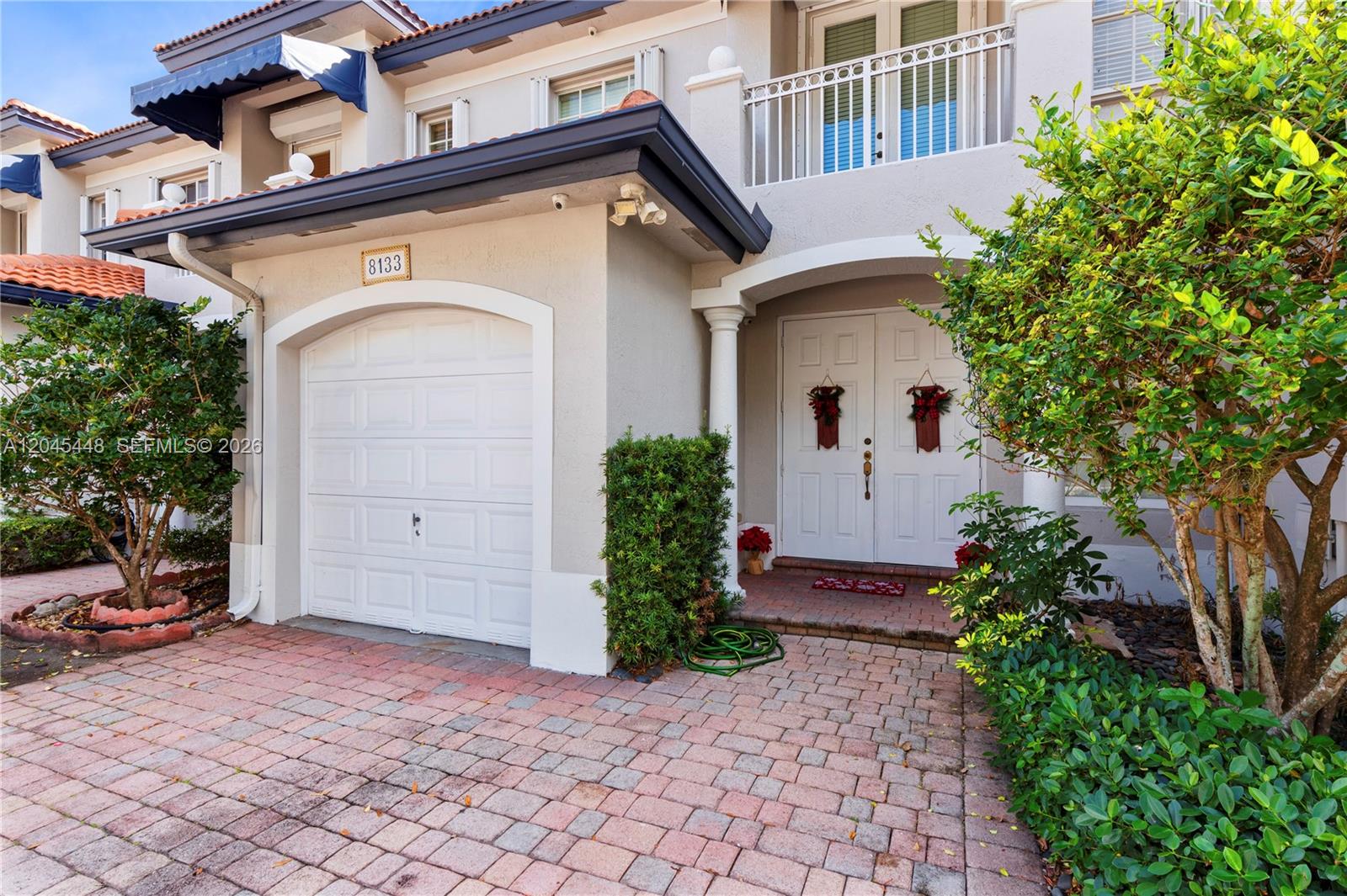 A two-story townhouse exterior features a white garage door, double front doors, and brick pavers — 8133 SW 118th Ct # 8133, Miami FL 33183, MIAMI, FL