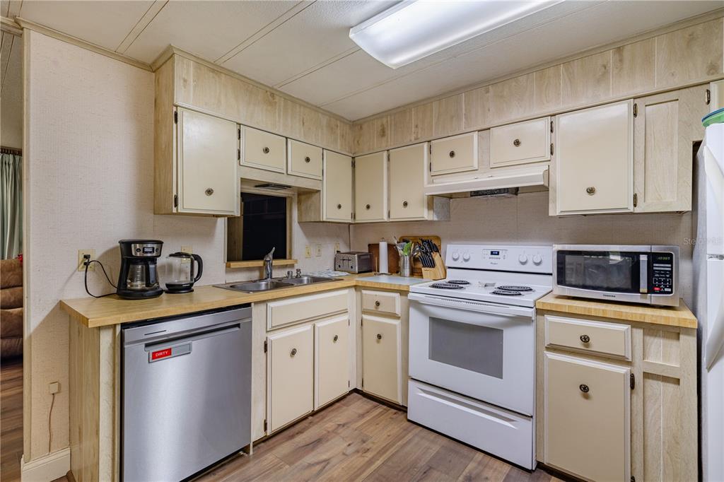 A kitchen features light-colored cabinets, a stainless steel dishwasher, a white stove, and wood-look flooring — 35737 SHELLEY DRIVE, LEESBURG, FL