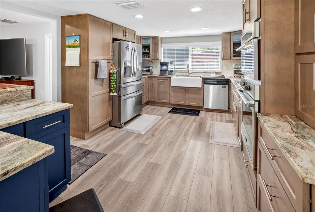 A kitchen features light wood cabinets, stainless steel appliances, blue island cabinetry, and granite countertops — 10627 MCINTOSH ROAD, THONOTOSASSA, FL