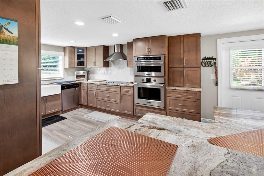 A kitchen features wood cabinets, stainless steel appliances, and a stone-topped island — 10627 MCINTOSH ROAD, THONOTOSASSA, FL