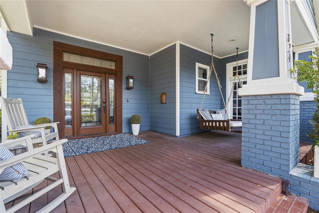 A covered front porch with blue siding, a wooden deck, a swing, and rocking chairs — 824 S ROME AVENUE, TAMPA, FL