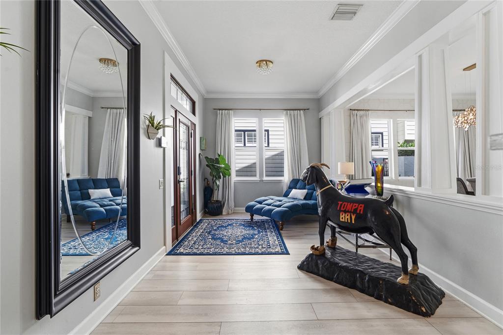 A bright entryway features light wood flooring, a large wall mirror, and a goat statue — 824 S ROME AVENUE, TAMPA, FL