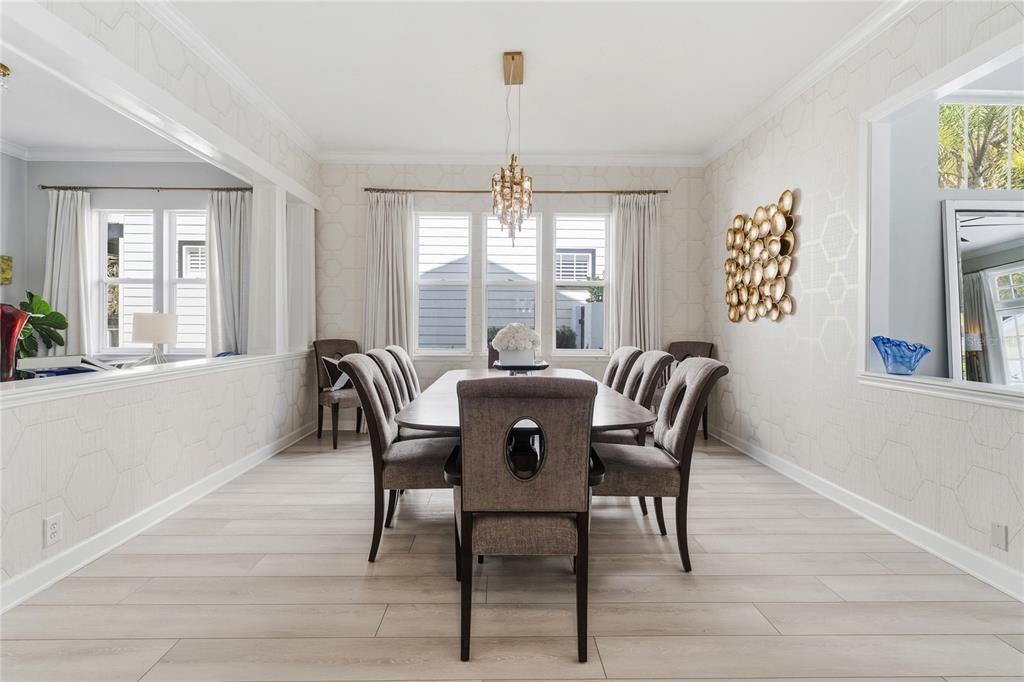 A dining room features a long table, upholstered chairs, light wood flooring, and patterned wallpaper — 824 S ROME AVENUE, TAMPA, FL