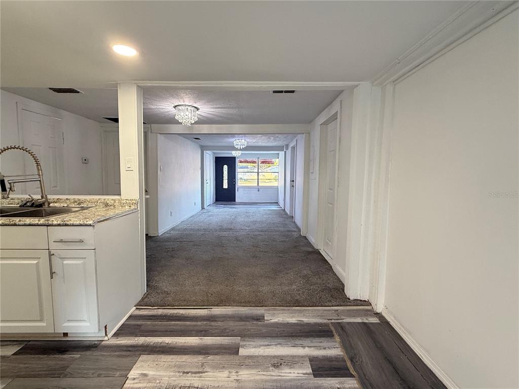 A kitchen with granite countertops overlooks a living area with gray carpeting and white walls — 408 LONGFELLOW BOULEVARD, LAKELAND, FL