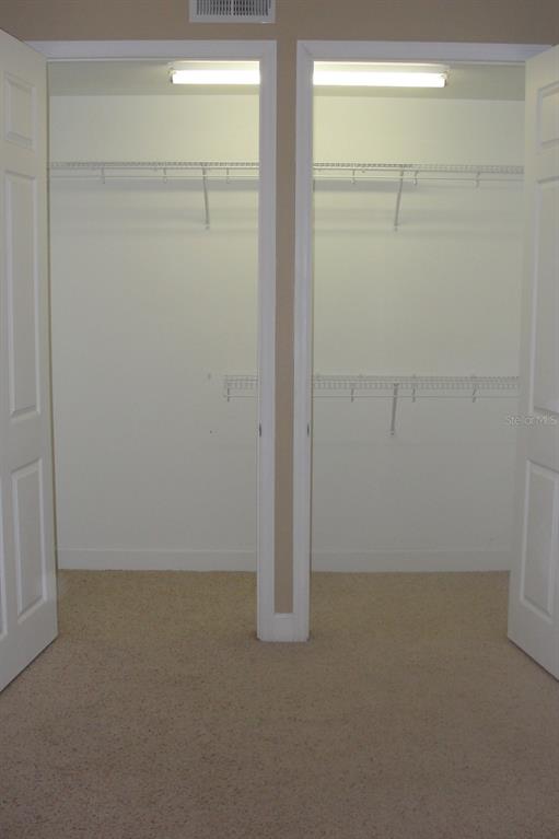 A walk-in closet with beige carpet, white walls, and wire shelving units — 2075 HERITAGE KEY BOULEVARD, KISSIMMEE, FL