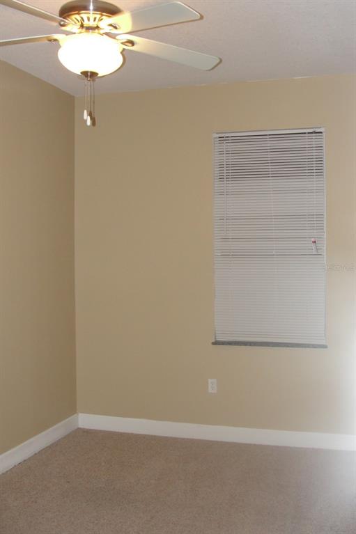 An empty bedroom features beige walls, carpeted flooring, a ceiling fan, and a window with blinds — 2075 HERITAGE KEY BOULEVARD, KISSIMMEE, FL