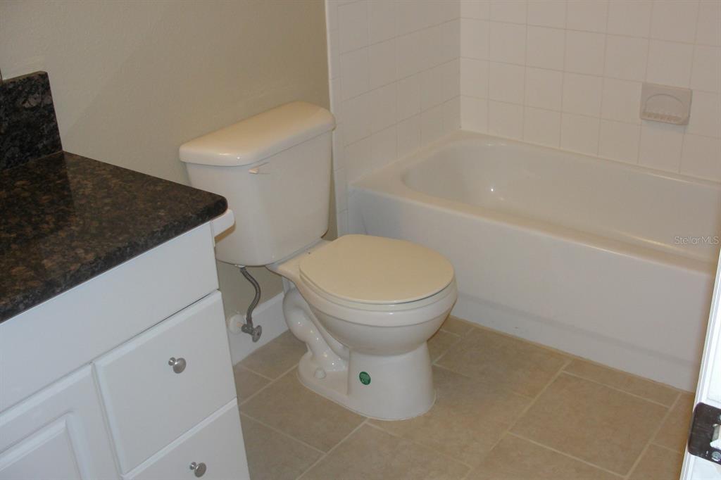 A bathroom features a white toilet, a bathtub with white tile, and a dark countertop — 2075 HERITAGE KEY BOULEVARD, KISSIMMEE, FL