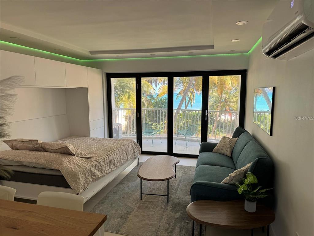 A studio apartment features a bed, sofa, and sliding glass doors opening to a balcony — 4633 AVE ISLA VERDE UNIT L202, CAROLINA, PR