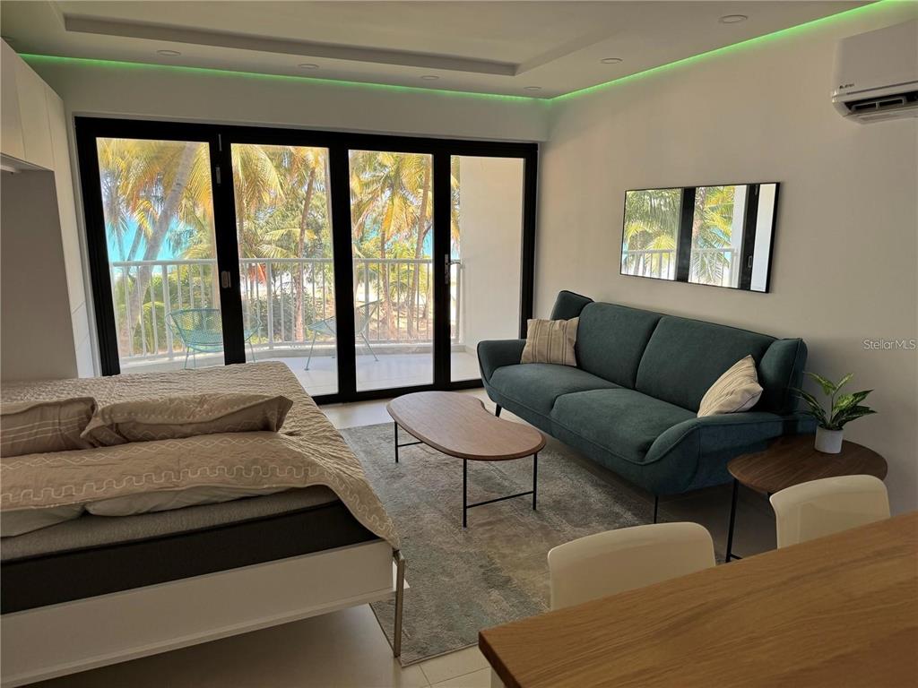 A modern studio apartment features a bed, sofa, coffee table, and sliding doors to a balcony — 4633 AVE ISLA VERDE UNIT L202, CAROLINA, PR