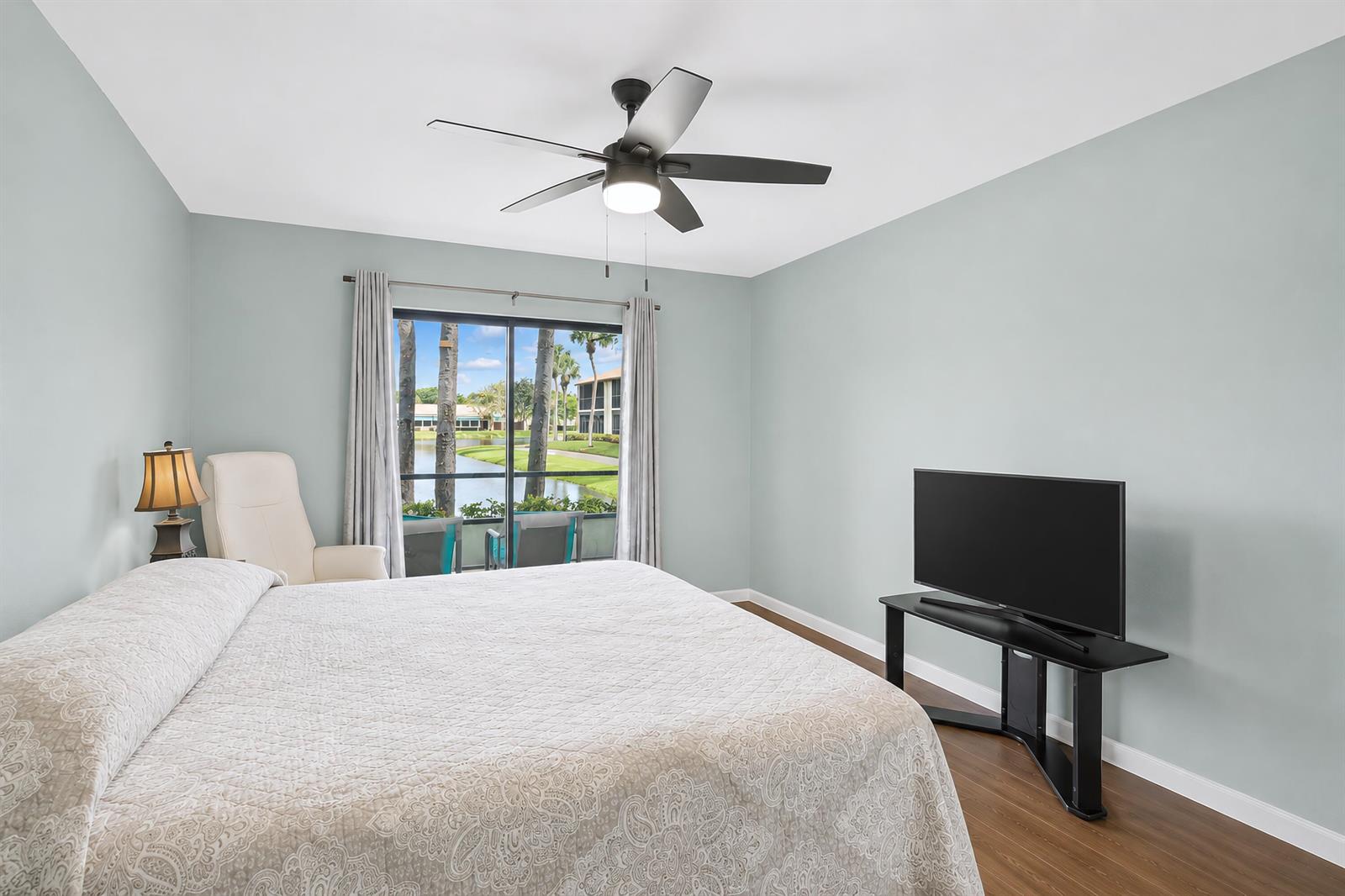 A bedroom features a bed, a television on a stand, and a sliding glass door — 7892 Willow Springs Drive # 1517, FL 33467, FL