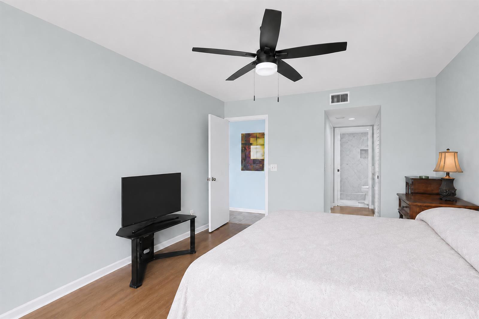 A bedroom features light blue walls, wood-look flooring, a ceiling fan, and an attached bathroom — 7892 Willow Springs Drive # 1517, FL 33467, FL