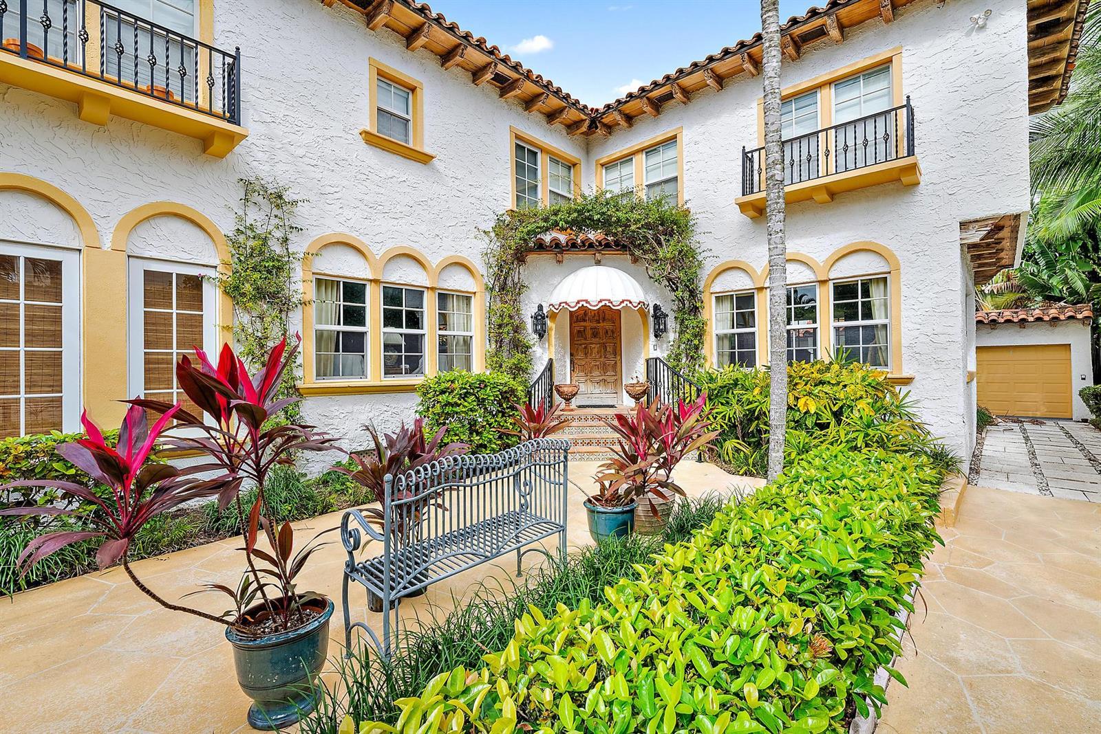 A Mediterranean-style home with a white stucco facade, yellow trim, and a central arched entryway — 325 Seaspray Avenue, Palm Beach FL 33480, PALM BEACH, FL
