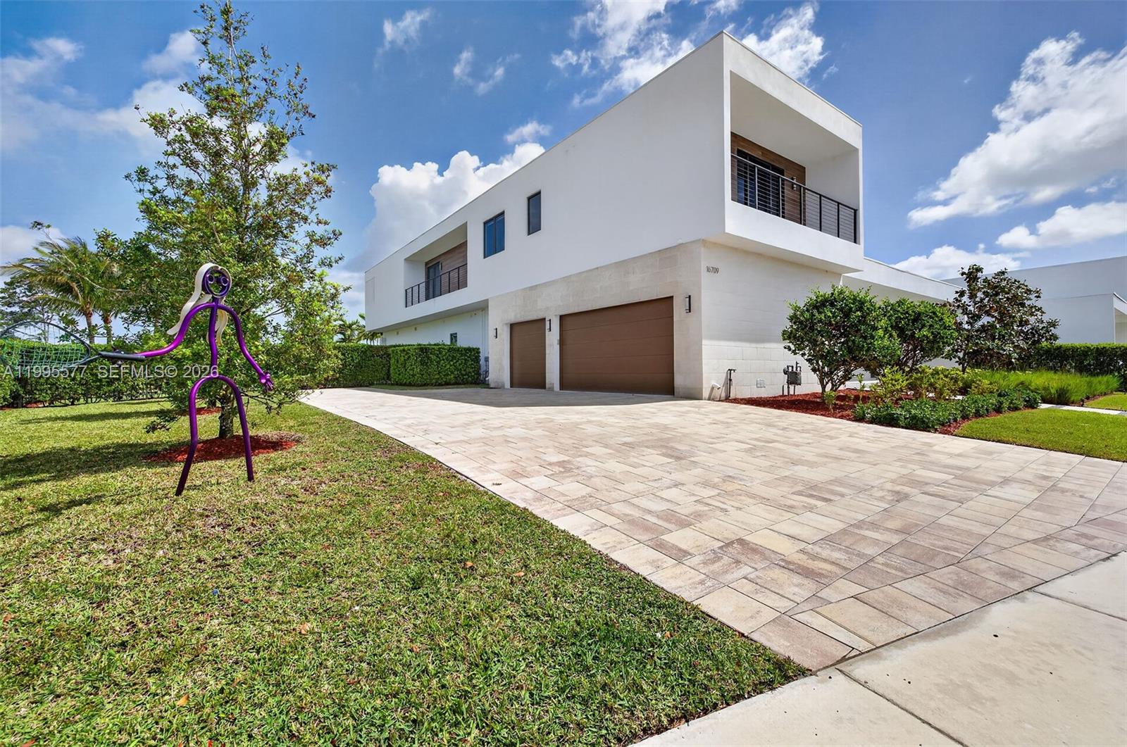 A modern two-story house with a paved driveway, brown garage doors, and a purple sculpture — 16709 Botaniko Drive North, Weston FL 33326, WESTON, FL