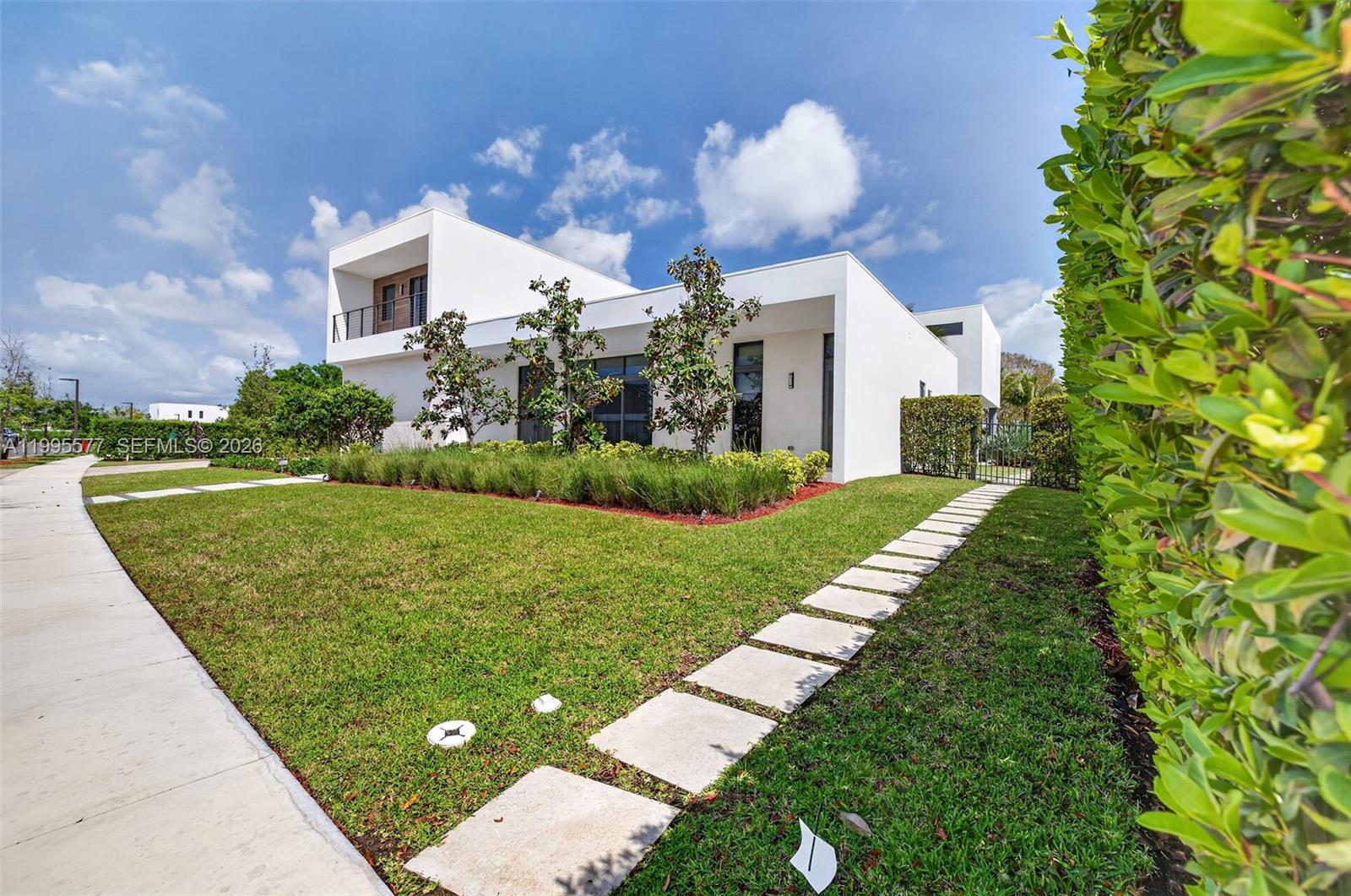 A modern white two-story house features a manicured lawn and a stone paver walkway — 16709 Botaniko Drive North, Weston FL 33326, WESTON, FL