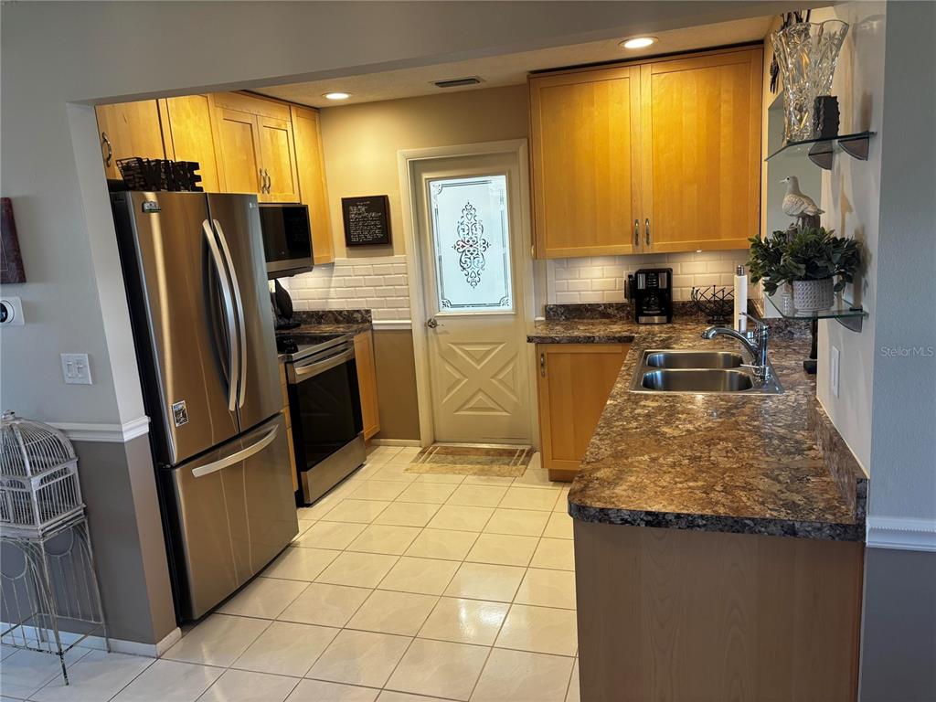 A kitchen features light wood cabinets, stainless steel appliances, a tiled floor, and laminate countertops — 4172 100TH AVENUE N, PINELLAS PARK, FL
