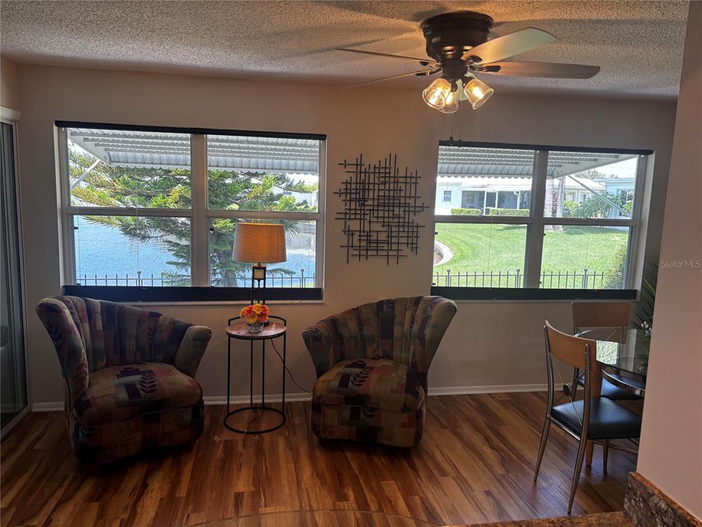 A room with two patterned armchairs, a small side table, and a dining set near windows — 4172 100TH AVENUE N, PINELLAS PARK, FL