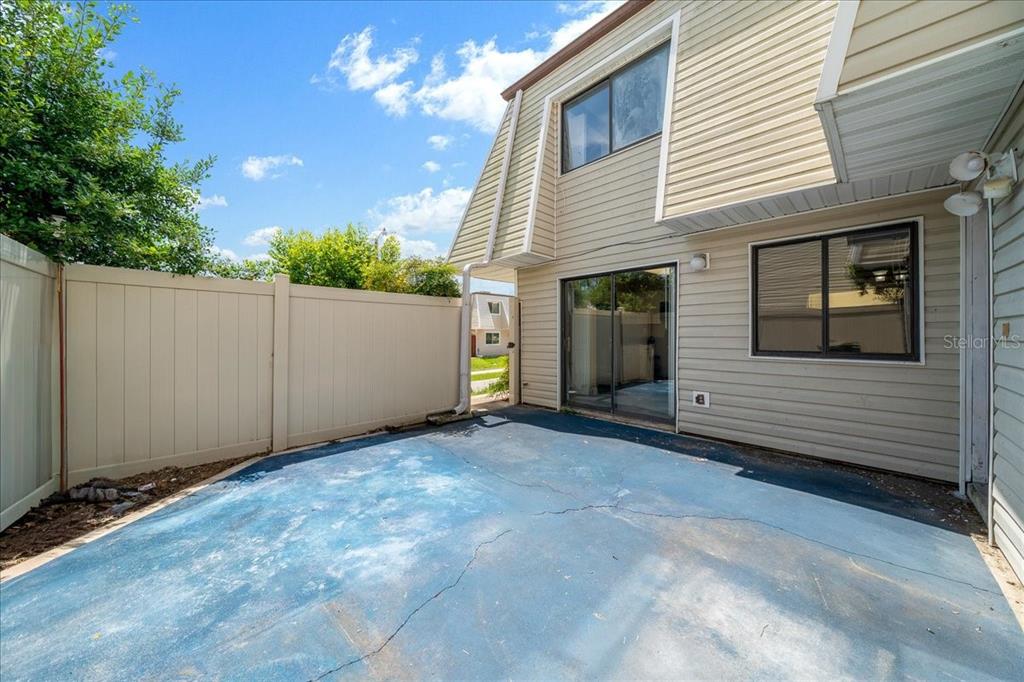A blue concrete patio sits beside a two-story house with beige siding and a fence — 2142 NE 45TH AVENUE UNIT 2, OCALA, FL