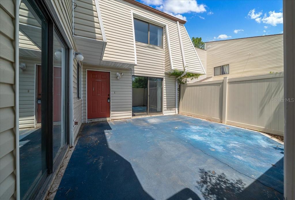 A view of a small backyard patio with a red door and sliding glass doors — 2142 NE 45TH AVENUE UNIT 2, OCALA, FL